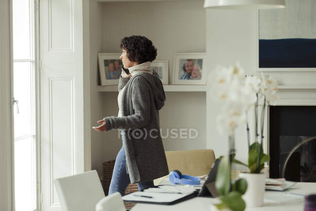 Woman working from home talking on smart phone at window — Stock Photo