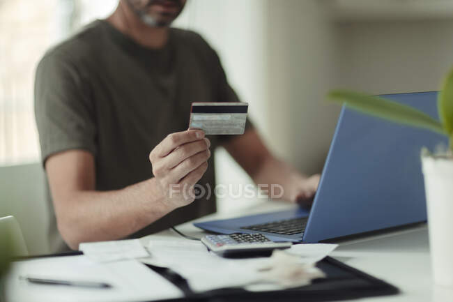 Man with credit card online shopping at laptop — Stock Photo