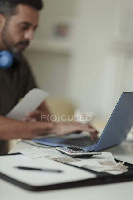Uomo con ricevute e calcolatrice pagare le bollette al computer portatile — Foto stock
