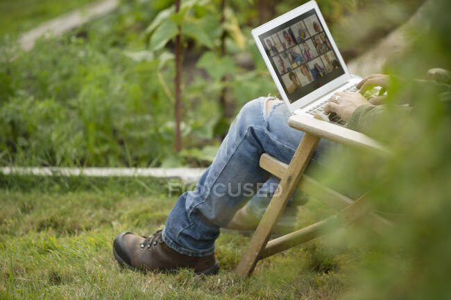 El hombre que trabaja en el portátil en el huerto - foto de stock