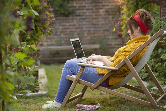Жінка працює на ноутбуці в саду — стокове фото