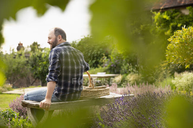 Happy man taking. break from gardening on bench in summer garden — Stock Photo