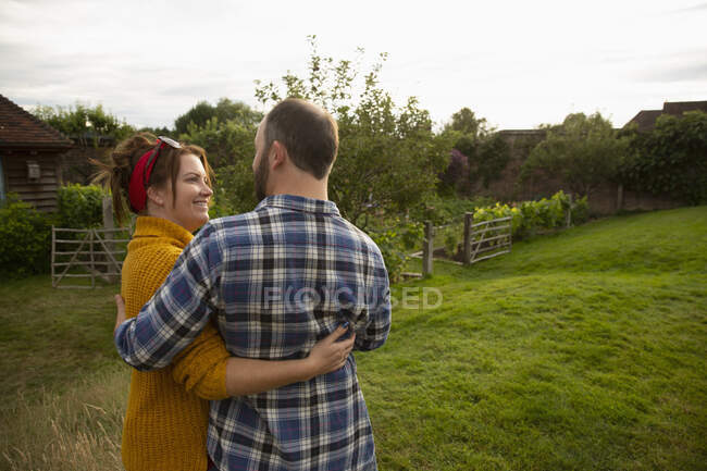 Happy affectionate couple hugging in idyllic cottage garden — Stock Photo