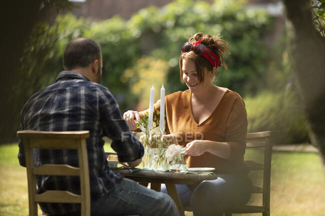 Happy couple enjoying cake at table in summer garden — Stock Photo