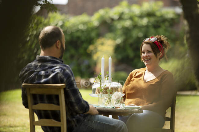 Happy couple enjoying cake at summer garden table — Stock Photo