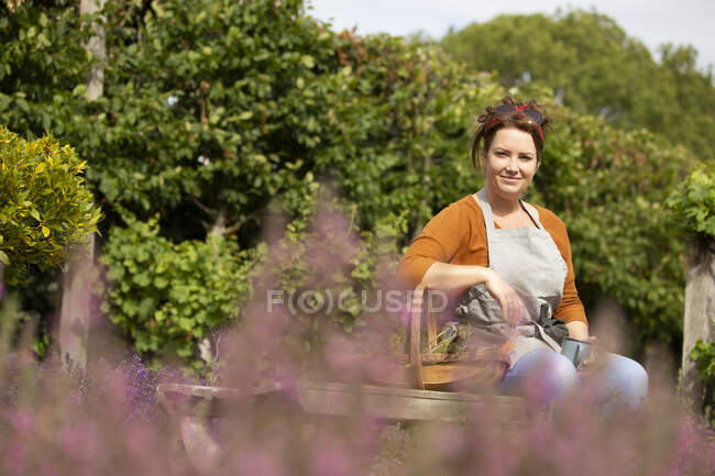 Портрет щасливої жінки, яка відпочиває від садівництва в сонячному саду — стокове фото