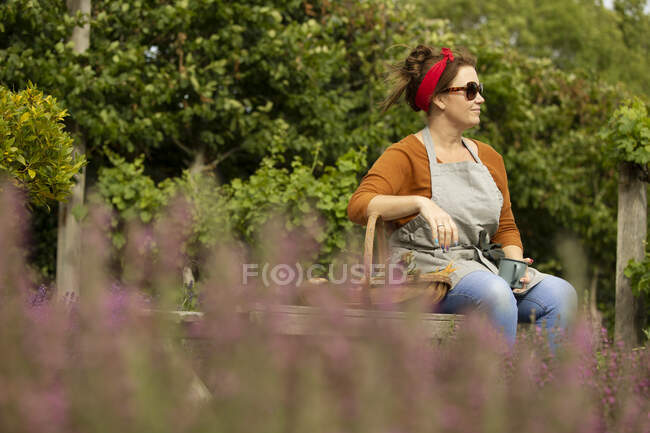 Mulher de óculos de sol fazendo uma pausa de jardinagem no quintal de verão — Fotografia de Stock