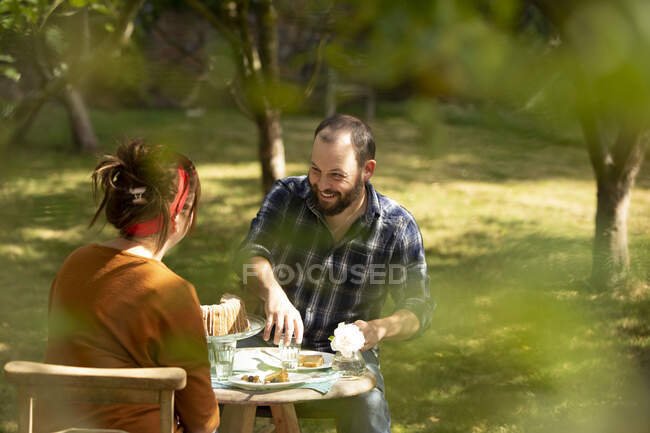 Glückliches Paar genießt Kuchen am sommerlichen Gartentisch — Stockfoto