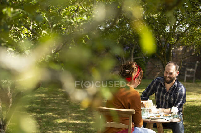 Paar genießt Kuchen am Tisch im sonnigen Obstgarten — Stockfoto