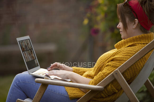 Frau benutzt Laptop im Rasenstuhl — Stockfoto