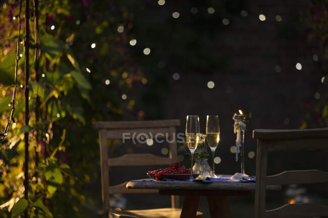 Flautas de champanhe e groselhas vermelhas na mesa no idílico jardim de verão — Fotografia de Stock
