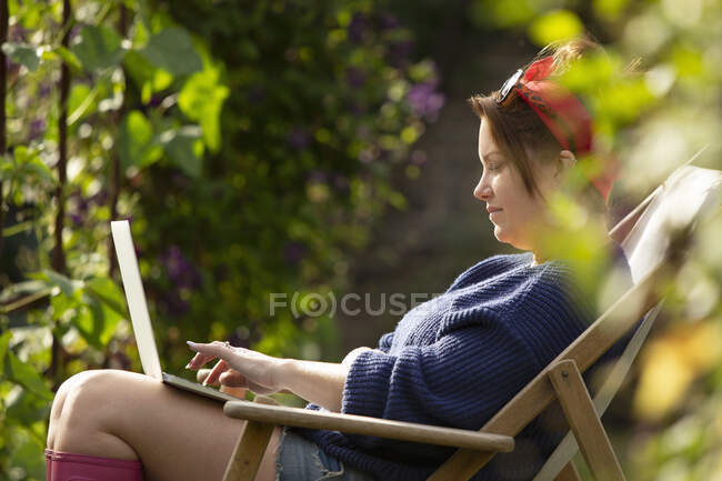 Frau benutzt Laptop im sonnigen Sommergarten — Stockfoto