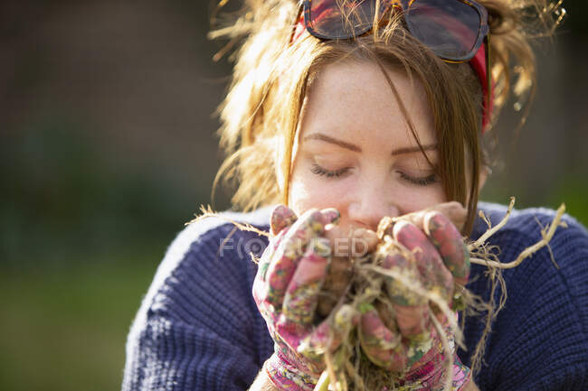 De cerca mujer oliendo patatas frescas cosechadas - foto de stock