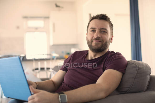 Retrato hombre confiado que trabaja desde casa en el ordenador portátil - foto de stock