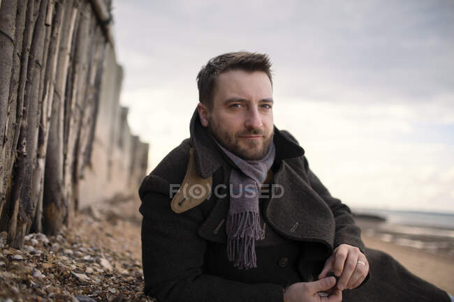 Retrato confiante bonito homem no casaco de inverno na praia — Fotografia de Stock