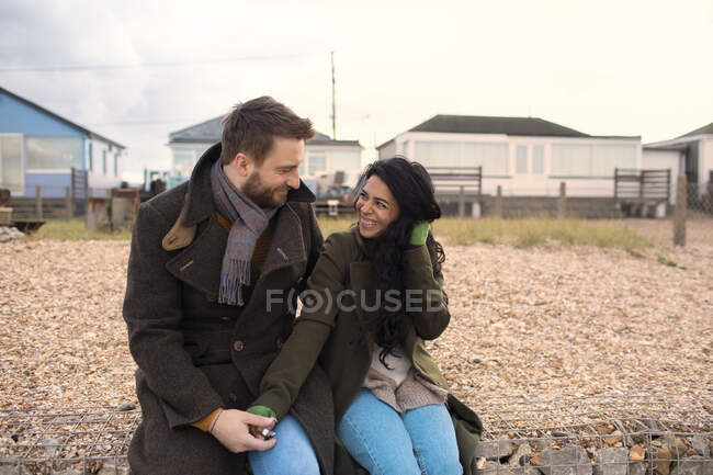Счастливая пара в зимних пальто за пределами пляжных домов — стоковое фото