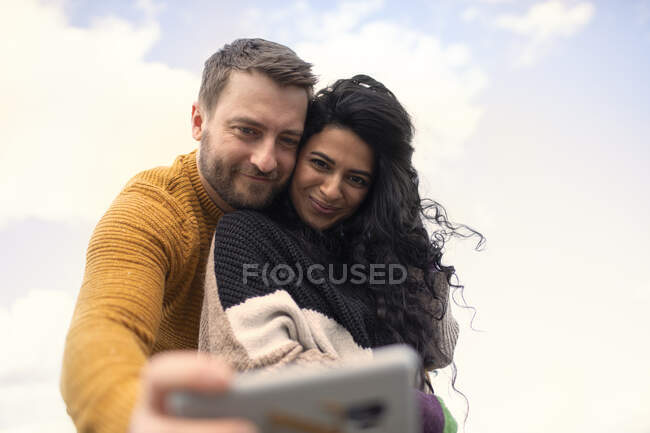Feliz pareja cariñosa en suéteres tomando selfie - foto de stock
