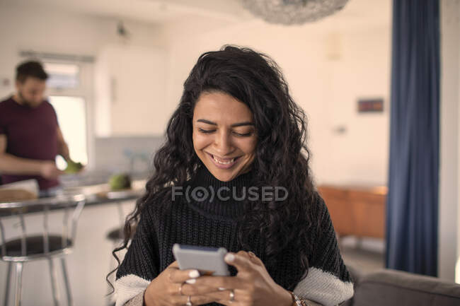 Щаслива жінка використовує смартфон вдома — стокове фото