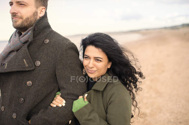 Casal feliz em casacos de inverno na praia — Fotografia de Stock