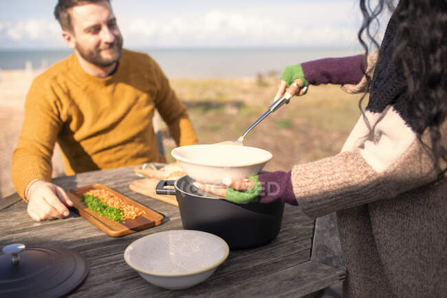 Una mujer sirviendo sopa. novio en soleado patio de playa - foto de stock