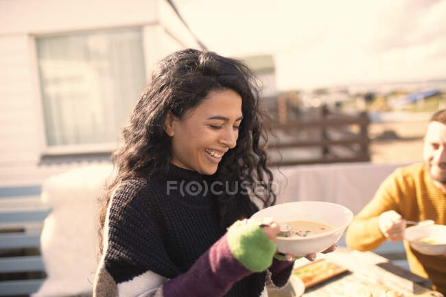 Happy woman enjoying chowder on sunny patio — Stock Photo
