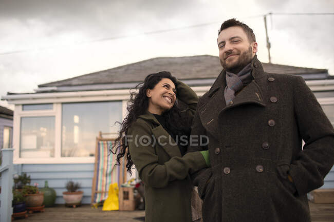 Retrato feliz pareja en abrigos de invierno fuera de casa - foto de stock