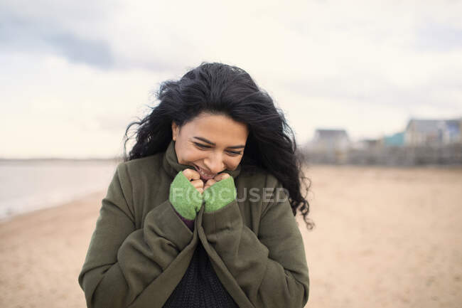 Glückliche Frau im Wintermantel am Strand — Stockfoto