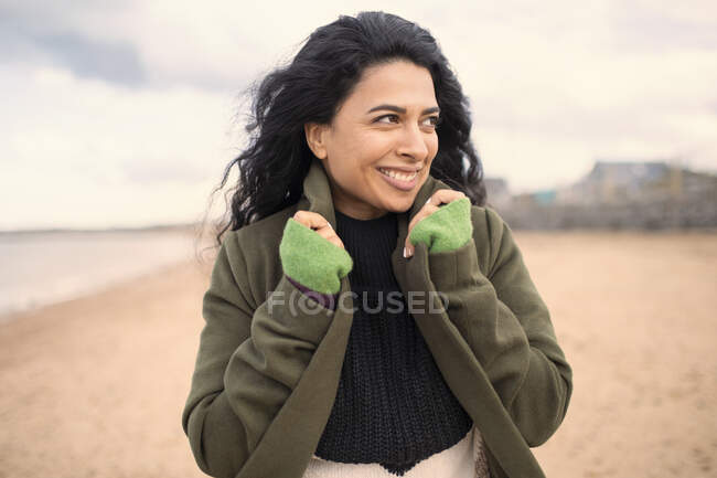 Glückliche schöne Frau im Wintermantel am Strand — Stockfoto