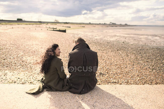 Couple en manteaux d'hiver sur la plage ensoleillée — Photo de stock