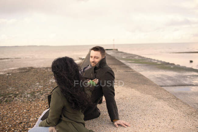 Couple en manteaux d'hiver sur jetée plage océan — Photo de stock
