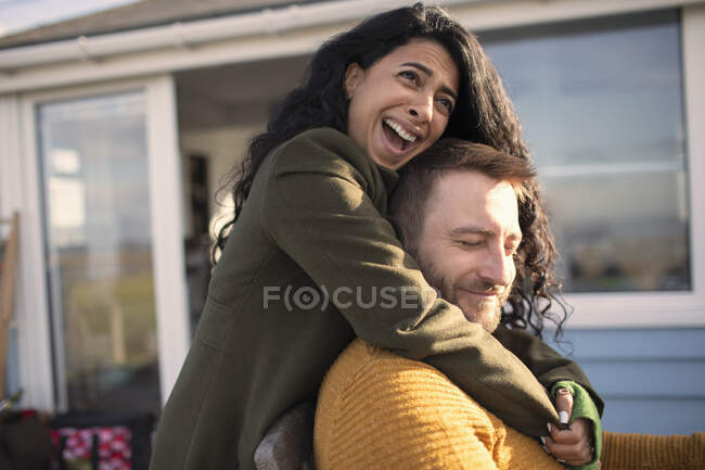 Счастливая любящая пара смеется и обнимается на патио — стоковое фото