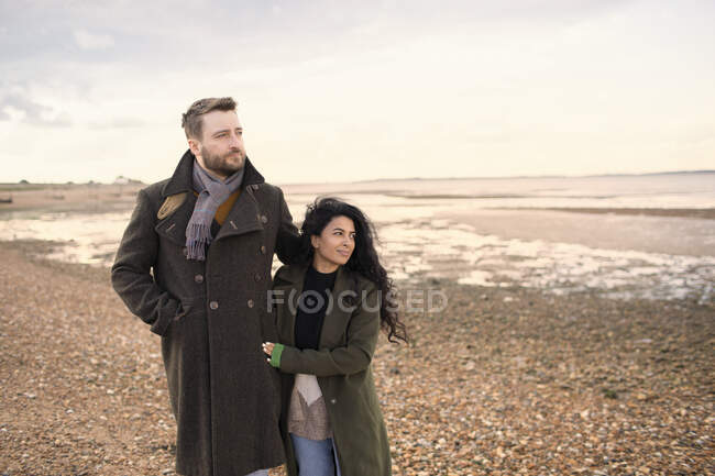 Casal afetuoso em casacos de inverno andando na praia do oceano — Fotografia de Stock