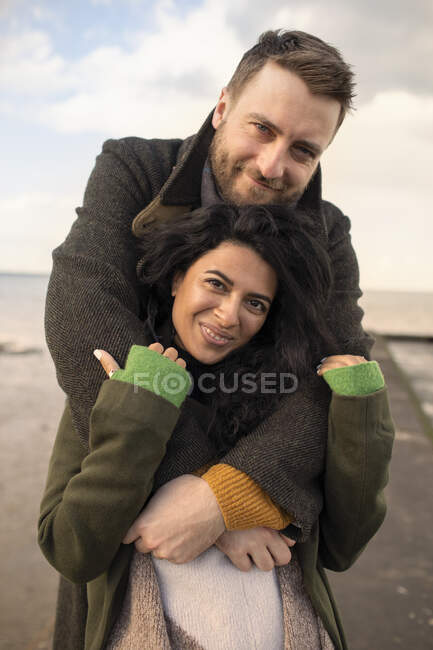 Retrato casal feliz em casacos de inverno abraçando — Fotografia de Stock