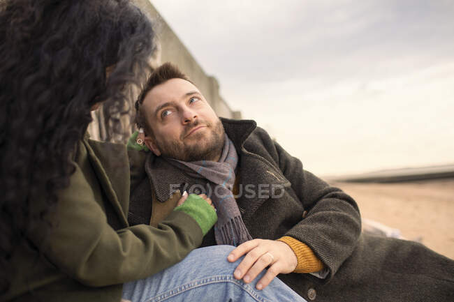 Affectionate couple in winter coats on beach — Stock Photo