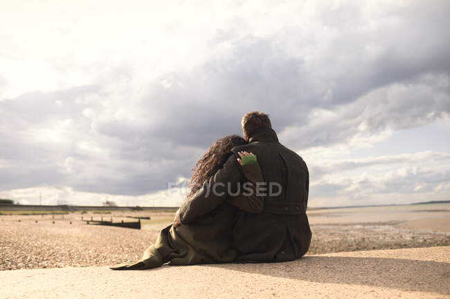 Sereno casal afetuoso abraçando na praia de inverno tranquila ensolarada — Fotografia de Stock