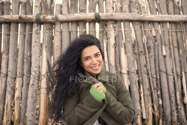 Portrait happy beautiful woman in winter coat at wood fence — Stock Photo