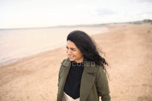 Счастливая женщина в зимнем пальто на пляже зимнего океана — стоковое фото