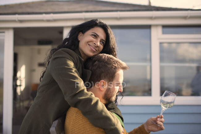 Happy couple hugging and drinking wine on patio — Stock Photo