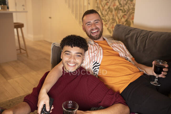 Portrait heureux gay mâle couple boire du vin sur canapé à la maison — Photo de stock