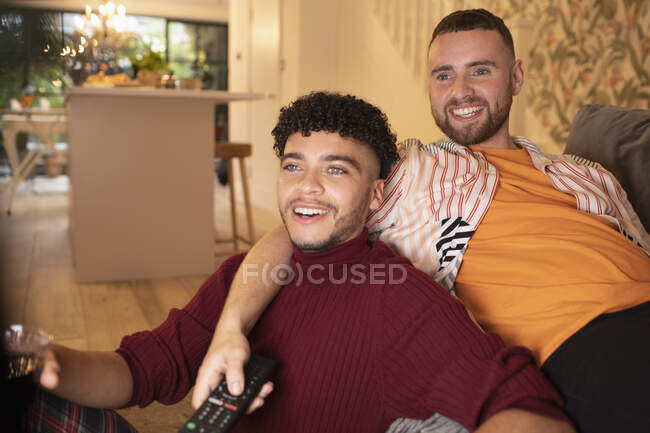 Feliz gay masculino casal assistindo TV no sofá — Fotografia de Stock