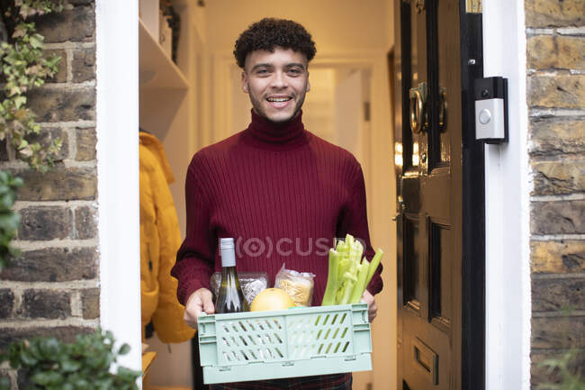 Portrait happy young man receiving grocery delivery at front door — Stock Photo