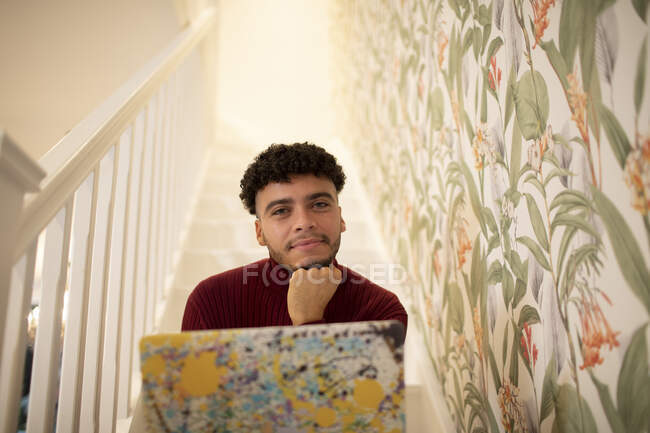 Портрет уверенный молодой человек с ноутбуком на лестнице дома — стоковое фото