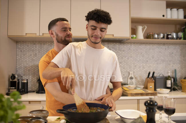 Ласковая гей-пара готовит на кухне — стоковое фото