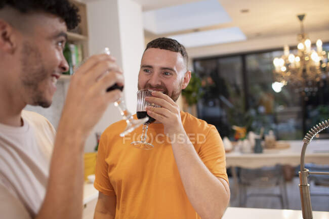 Щаслива гомосексуальна пара п'є червоне вино на кухні — стокове фото