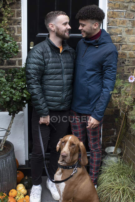 Happy gay male couple with dog on front stoop — Stock Photo