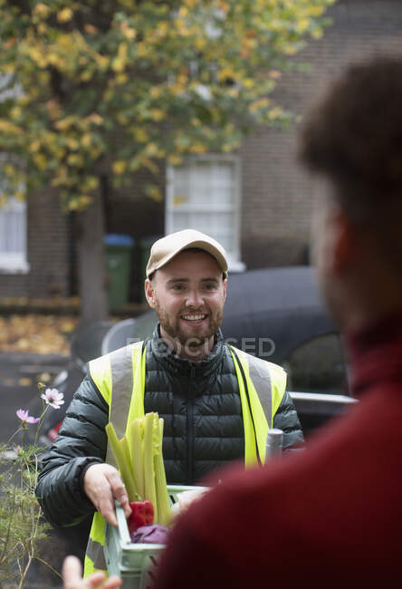 Friendly delivery man delivering groceries at front door — Stock Photo