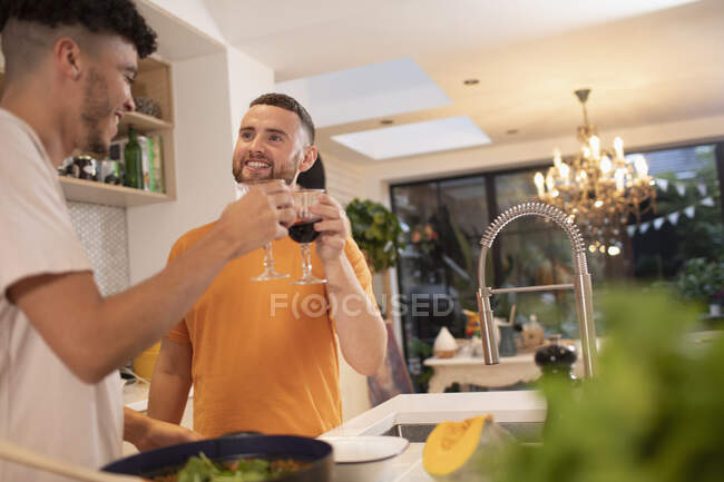Счастливая гей-пара пьет вино и готовит на кухне — стоковое фото