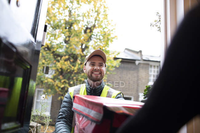 Friendly delivery man delivering food at front door — Stock Photo