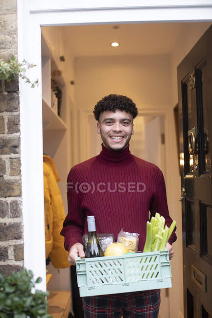 Retrato jovem feliz recebendo entrega de supermercado na porta da frente — Fotografia de Stock