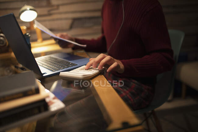 Young man with calculator paying bills at laptop in home office — Stock Photo